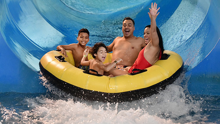 family in yellow tube on a blue slide at water park